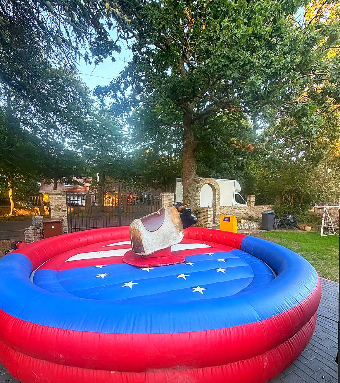 Mechanical rodeo bull with mottled hide on a red and blue inflatable landing area outdoors