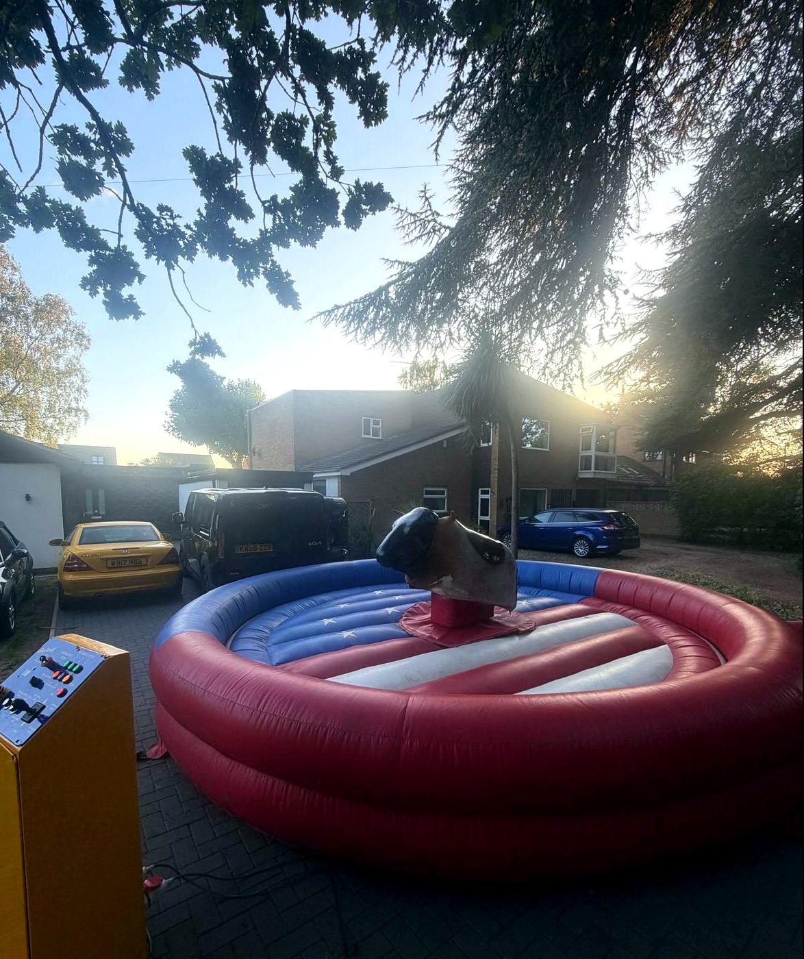 Mechanical rodeo bull in a blue and red inflatable ring, yellow control box on the left